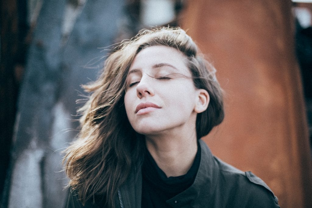 Bust shot of a white woman, looking peaceful and serene, with her eyes closed.