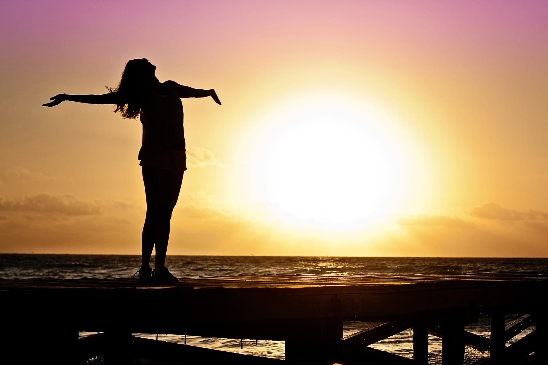 Silhouetted woman stretching and basking in the sunset.