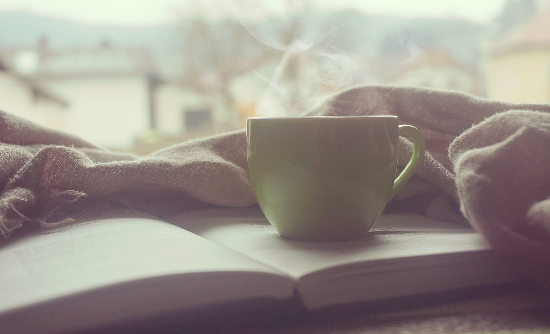 A steaming cup of coffee or tea placed directly on top of an open book. Really.